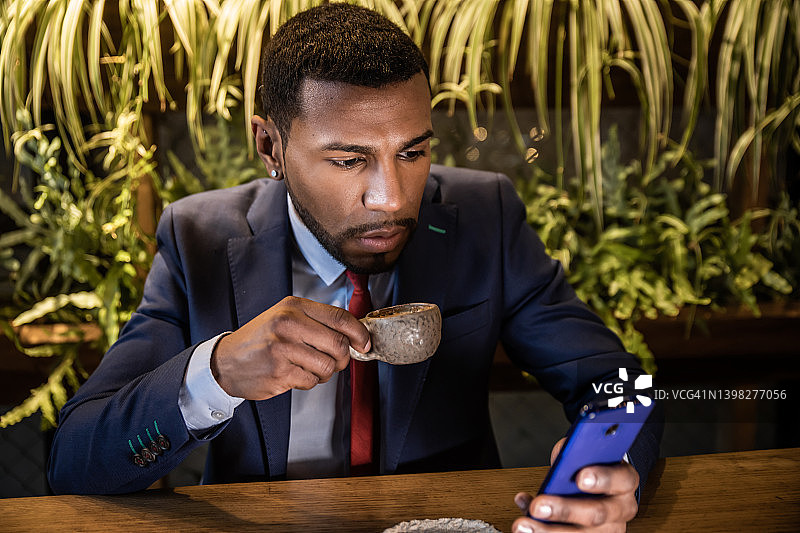 商务男士在咖啡店喝咖啡时使用手机图片素材
