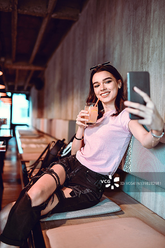 在酒吧自拍时喝果汁的可爱女人图片素材