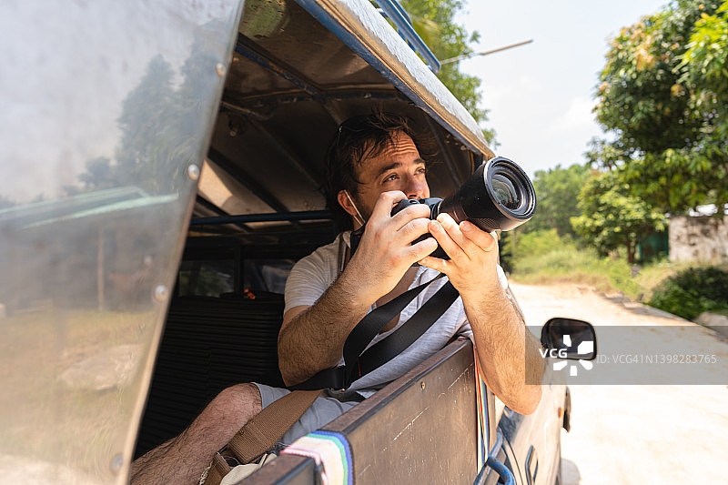 乘坐越野出租车用相机拍摄风景的男游客图片素材