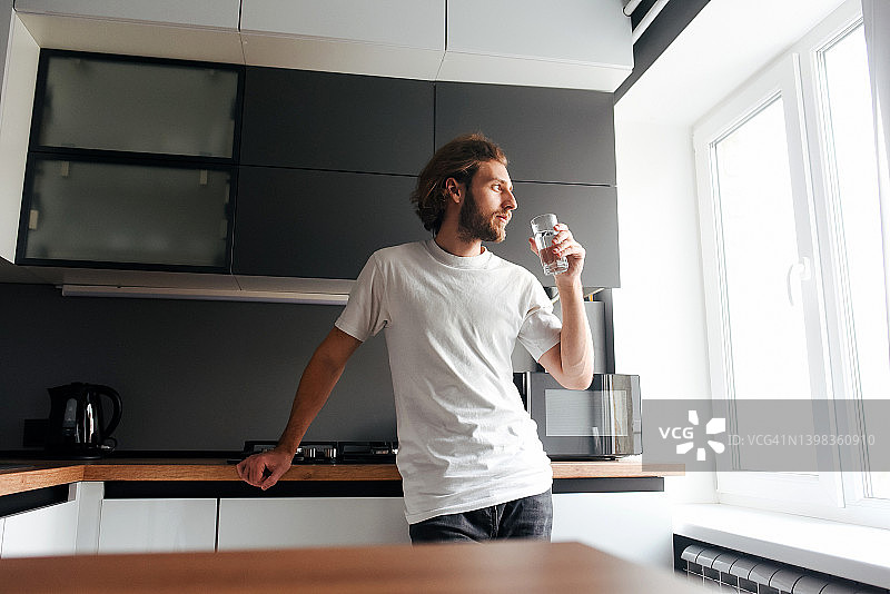帅气胡须男在厨房喝水图片素材