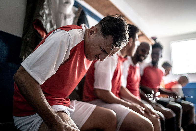 在更衣室里按压大腿的受伤足球运动员图片素材