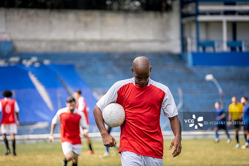 足球运动员手持足球离场图片素材