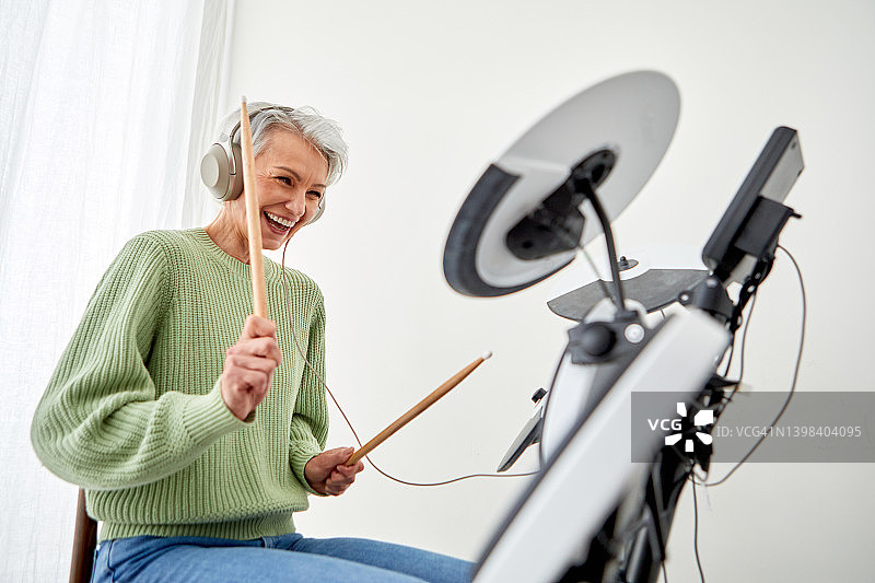快乐的老年妇女在工作室里演奏钹图片素材