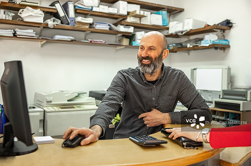在复印店使用电脑工作的白人男子图片素材