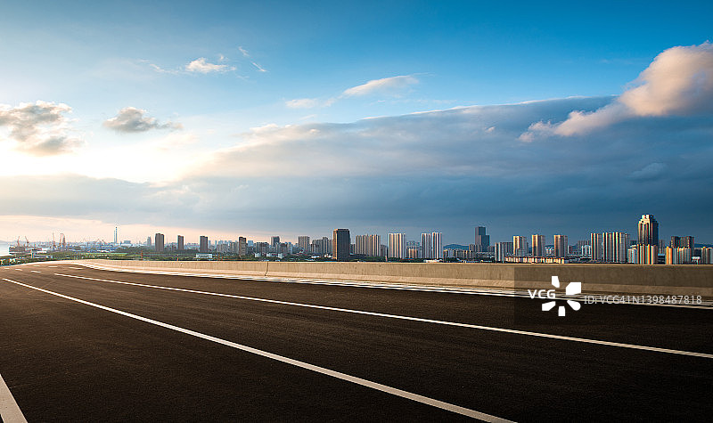 傍晚晴空下通往城市的沥青公路图片素材