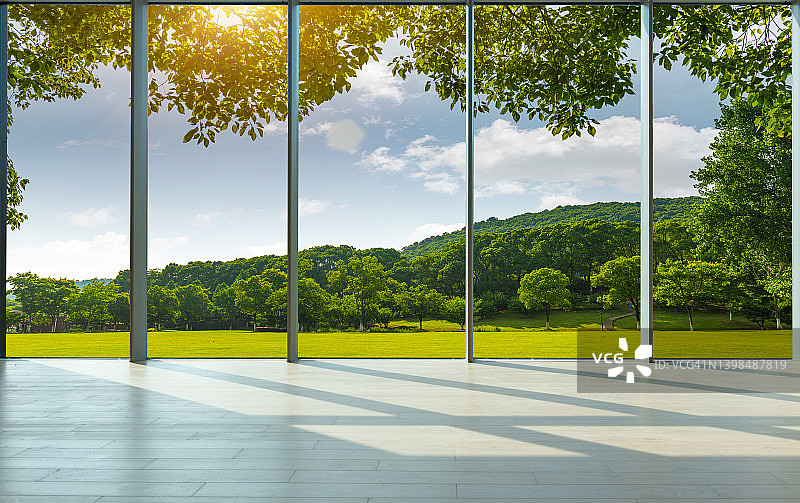 透过落地窗，窗外是公园草坪和森林图片素材