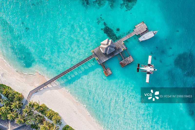马尔代夫海岸、码头别墅水上飞机顶视图、多尼木船和热带海滩的壮丽航拍景色。棕榈树、白色沙滩、海洋。奢华旅行和度假概念。图片素材