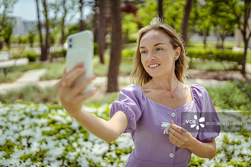 在户外使用手机拍照的美丽女人图片素材