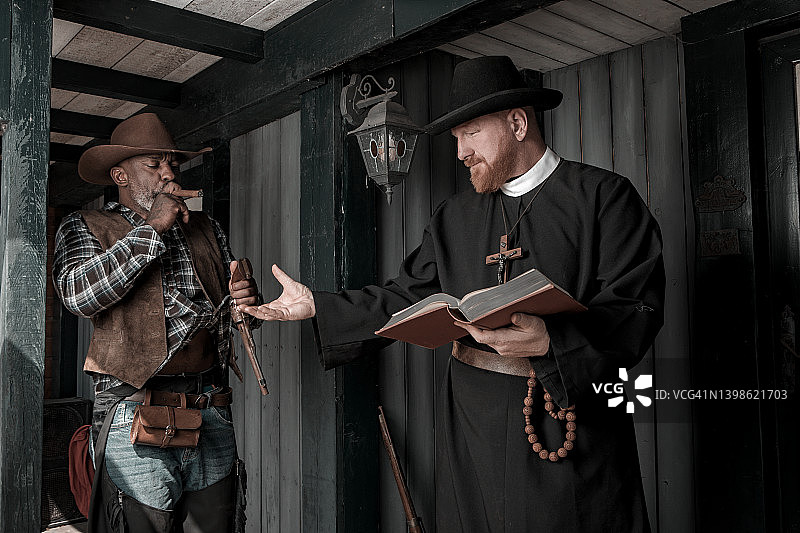 帅气黑人牛仔与牧师在狂野西部背景中图片素材