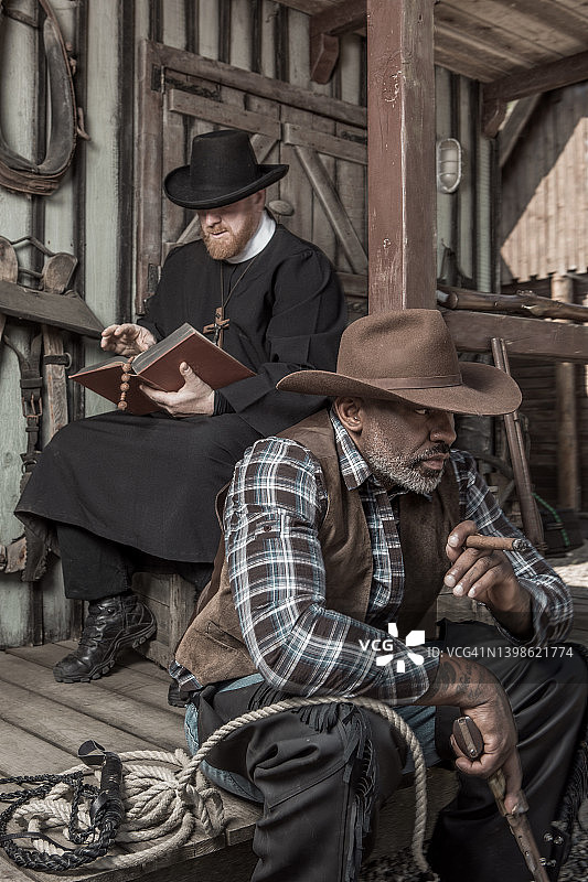 帅气黑人牛仔与牧师在狂野西部背景中图片素材