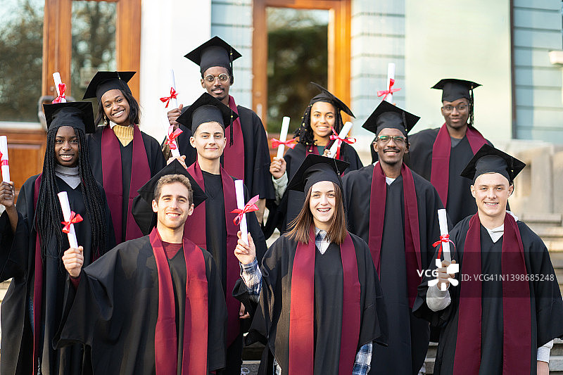 毕业生在大学前展示毕业文凭图片素材