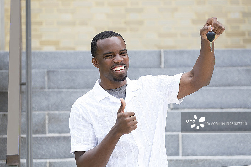 一位留着山羊胡的非裔美国千禧一代男子，拿着车钥匙，穿着白色衬衫，显得很兴奋。图片素材