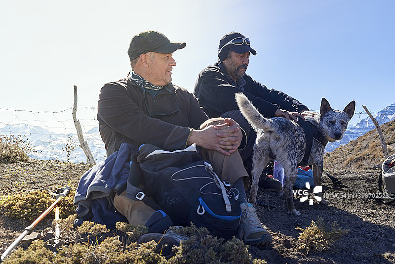 两位年长者在山区散步时与他们的狗一起休息图片素材