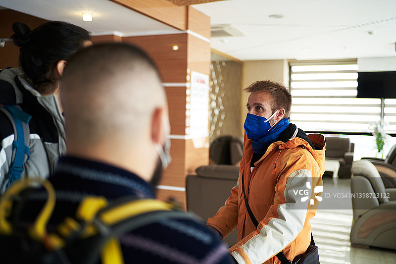 戴着面具的男人在酒店大堂与朋友交谈图片素材