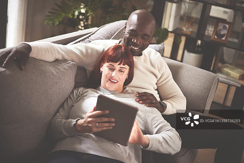 一对夫妇在家中沙发上使用平板电脑图片素材