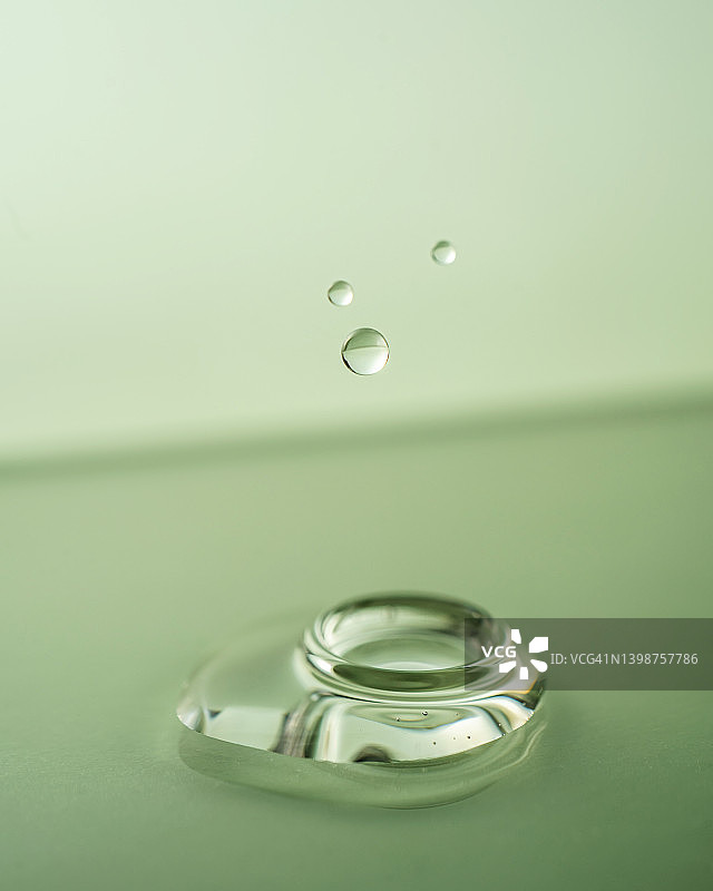 绿色背景上的一滴精油，精华液或其他化妆品图片素材