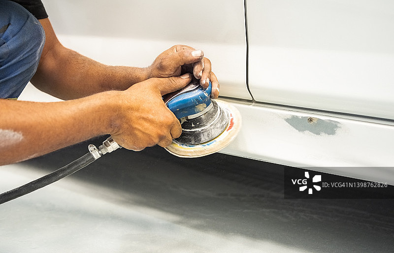 修理工在喷漆前用打磨机平滑汽车摇臂面板图片素材