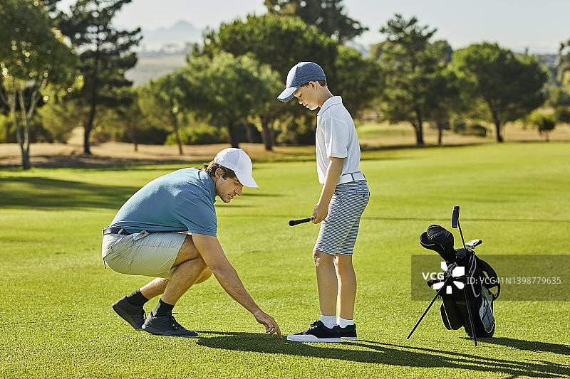 高尔夫球手在晴朗的一天教儿子打高尔夫球图片素材