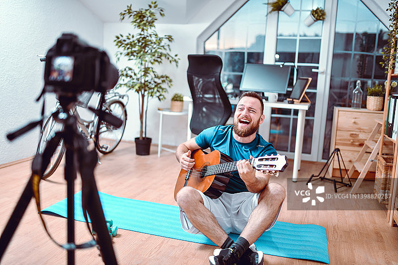 在家办公锻炼后录制吉他弹奏Vlog的男子图片素材