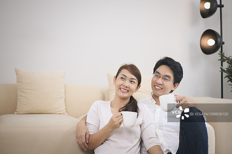 在新家中坐在地板上喝咖啡的迷人年轻情侣图片素材