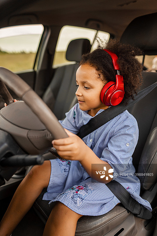 坐在车里假装驾驶的混血小女孩图片素材