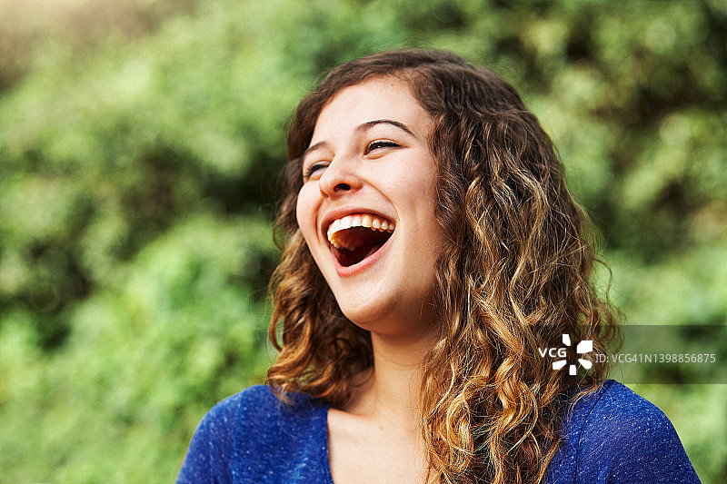 在阳光明媚的日子里，户外仰头大笑的漂亮年轻女人图片素材