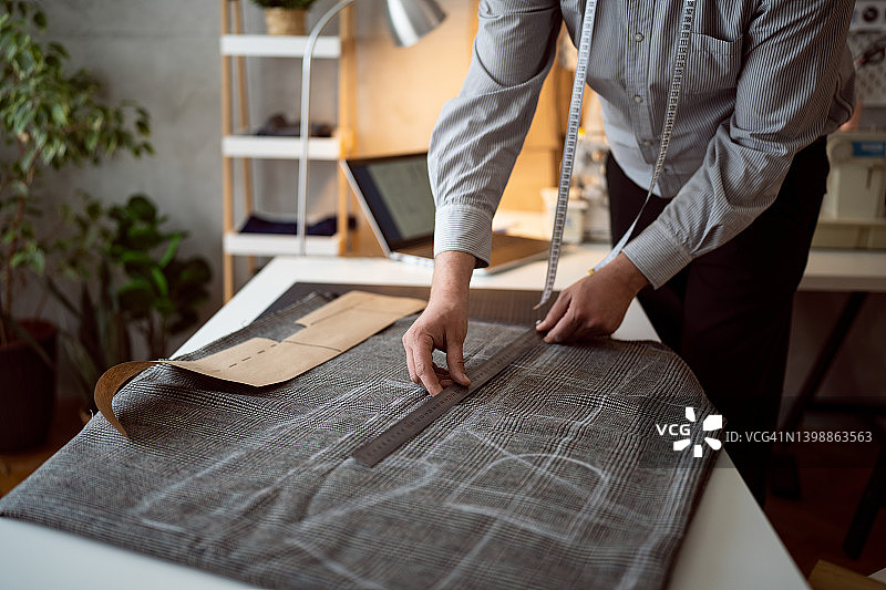 男裁缝用尺子在纺织品上测量图片素材