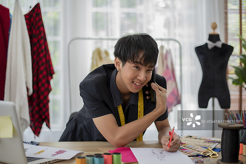 裁缝店里与顾客通电话的亚洲裁缝图片素材