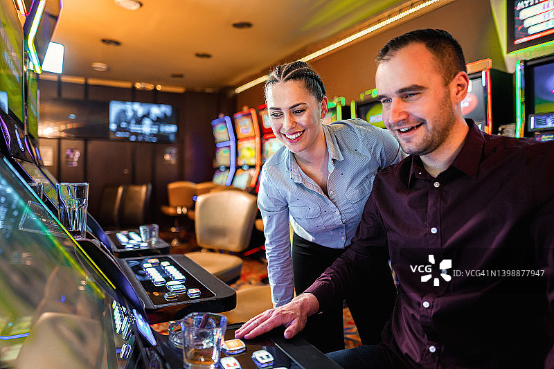 两名朋友在赌场玩老虎机图片素材