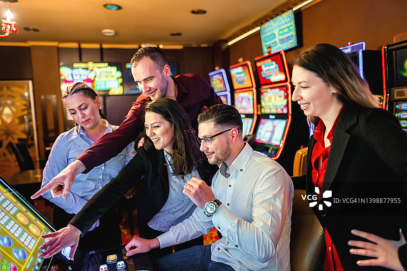 一群快乐的朋友玩老虎机并赢钱图片素材