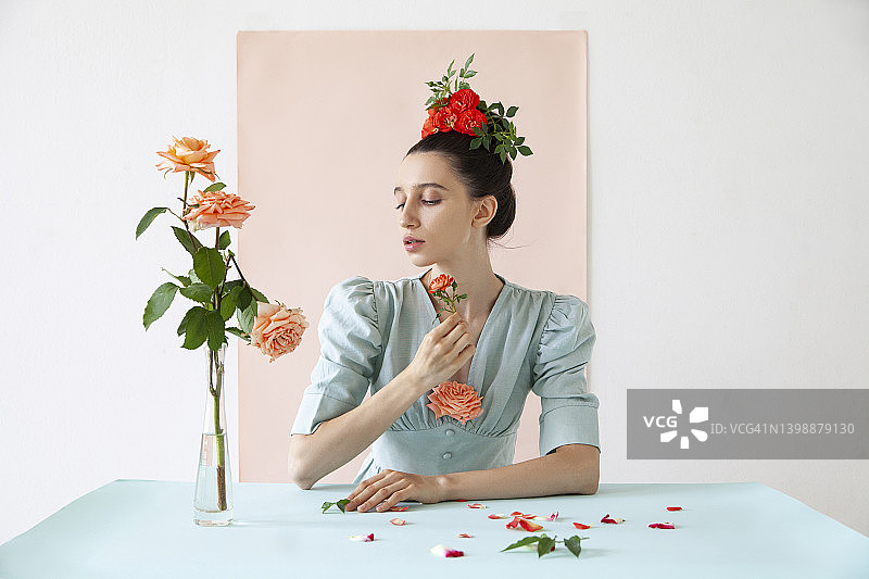 年轻女人拿着玫瑰花，粉色背景图片素材