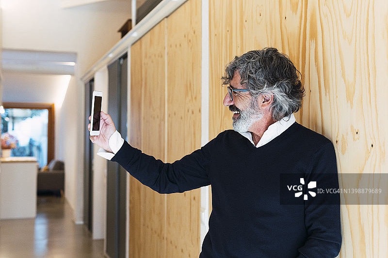 快乐的老年男人在家用手机自拍图片素材