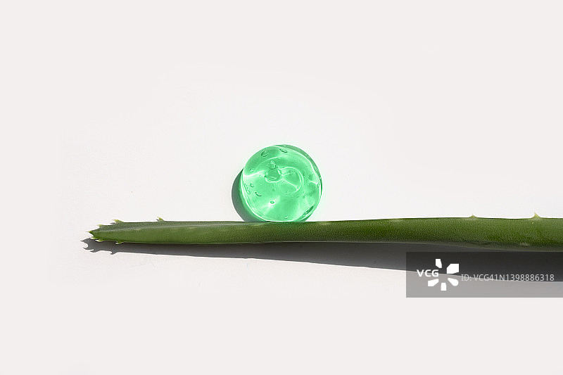 透明绿色液体精华，面部精华液或芦荟保湿清洁化妆品凝胶，含氧气泡和芦荟叶图片素材