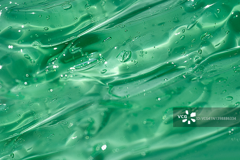 芦荟保湿清洁化妆品凝胶或面部精华，含氧气泡的精油在柔和的绿色薄荷或罗勒色背景上图片素材