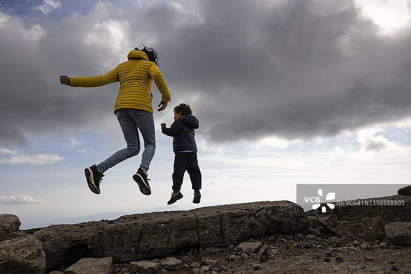 母子在壮丽的天空下跳跃图片素材