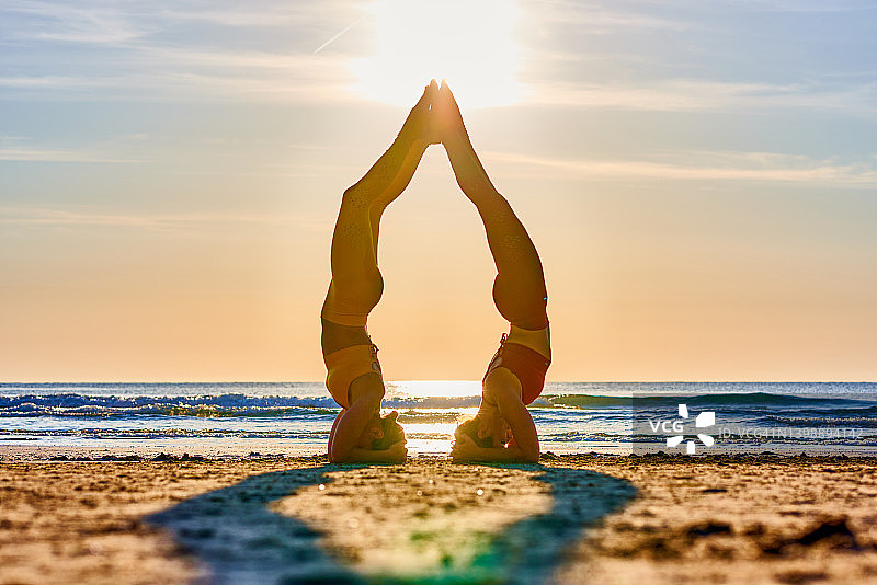 两名女子在日出时的海滩上表演 Acroyoga图片素材