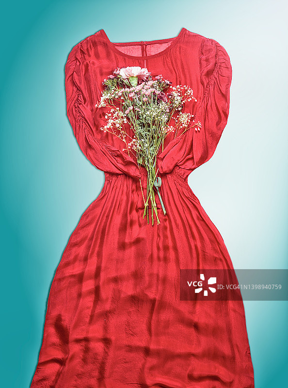 蓝色背景上的红色连衣裙和花束图片素材