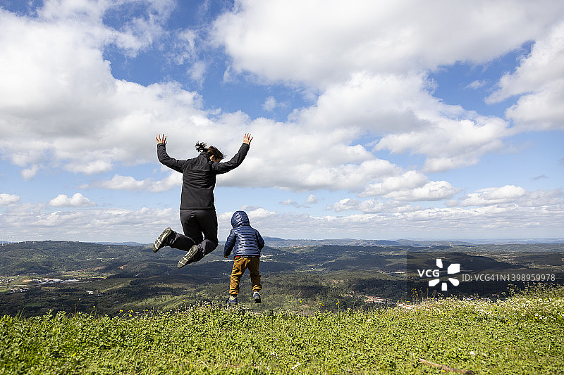 母子在绿色田野上跳跃图片素材
