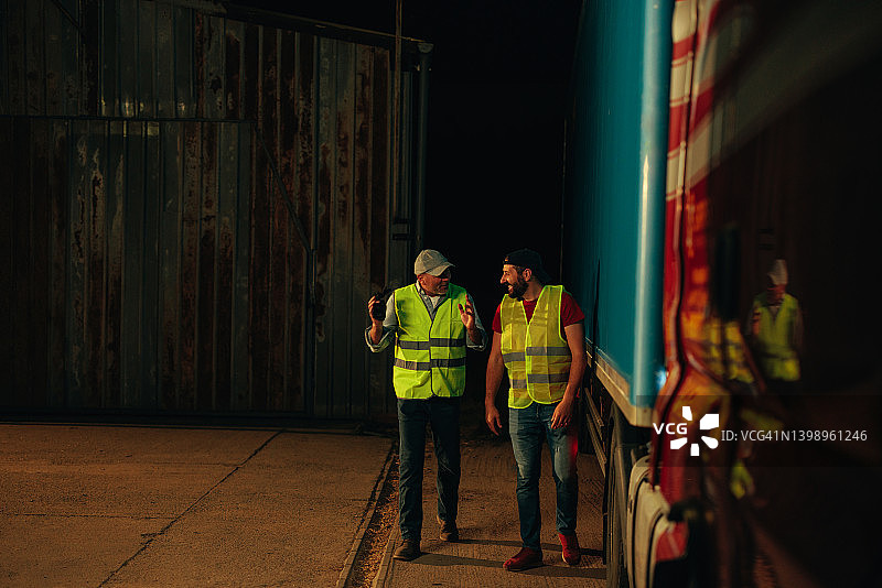 两名卡车司机站在卡车旁交谈图片素材