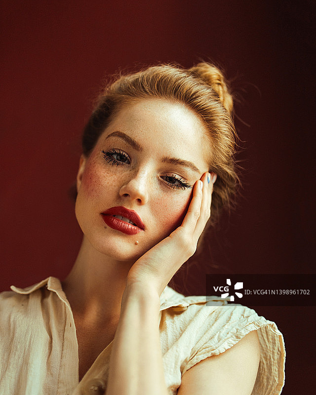 靠在红墙上的年轻困倦的女人图片素材