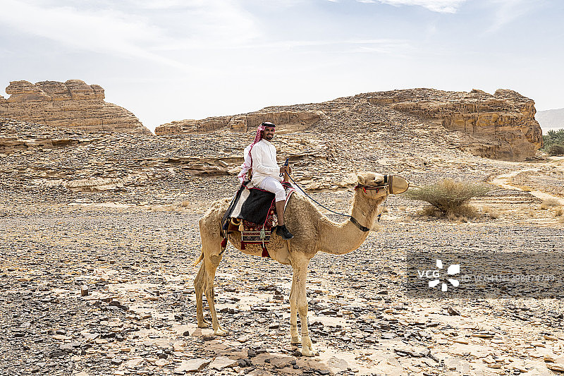 沙特阿拉伯旅行者骑单峰骆驼的沙漠肖像图片素材