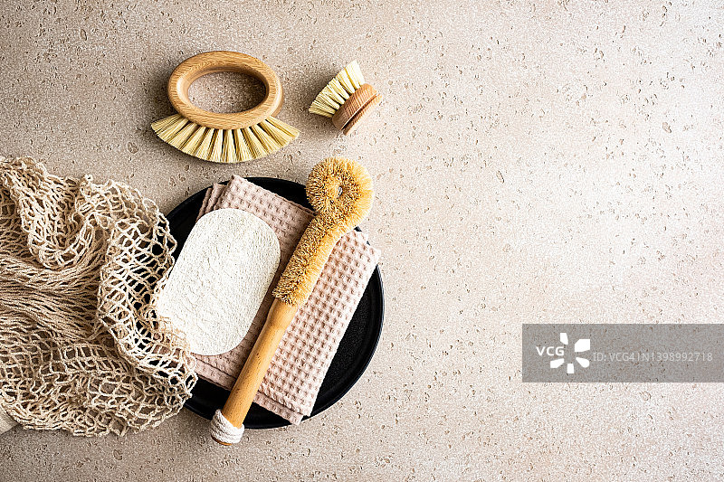 环保厨房清洁用品套装：木制洗碗刷、奶瓶刷、棉布毛巾、丝瓜海绵，黑色托盘上的可重复使用袋子图片素材