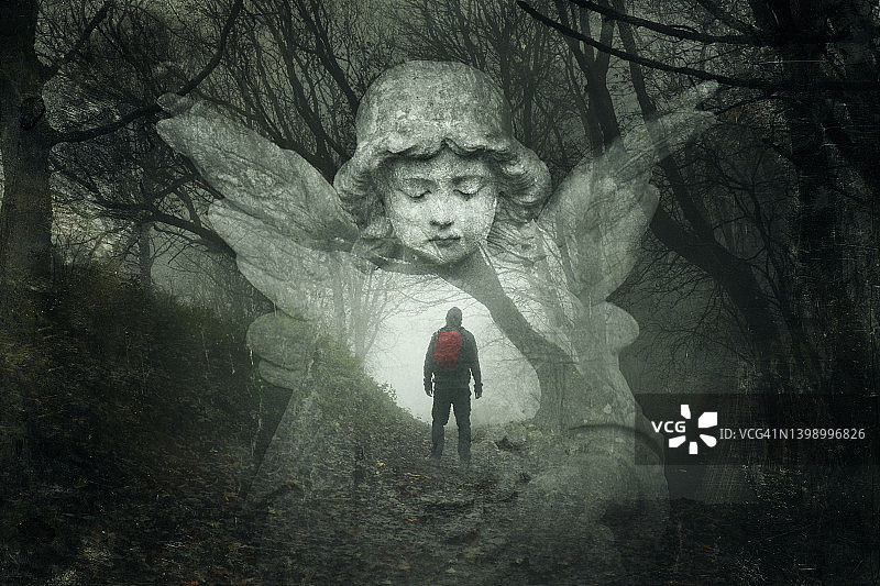徒步旅行者迷失在阴森的冬季森林中的神秘概念，顶部是墓地天使的双重曝光，带有粗犷的复古编辑效果。图片素材