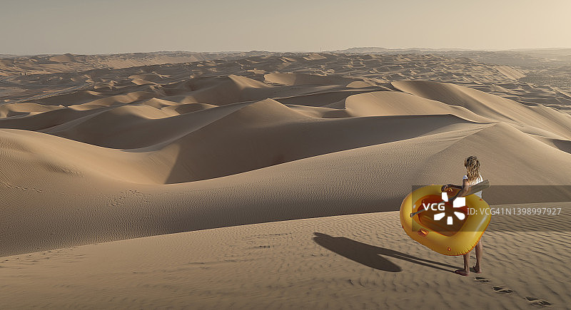 在沙漠中拿着充气筏的女人图片素材
