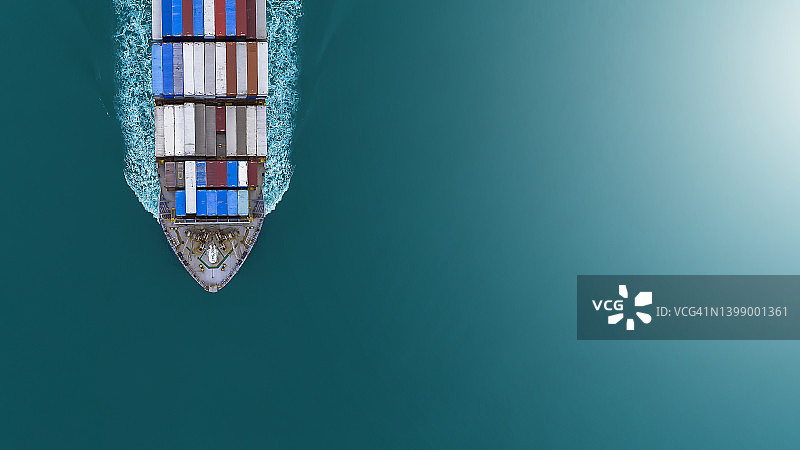 航拍：大型集装箱船在蓝色海面上高速航行，进出口、物流和国际航运业务图片素材