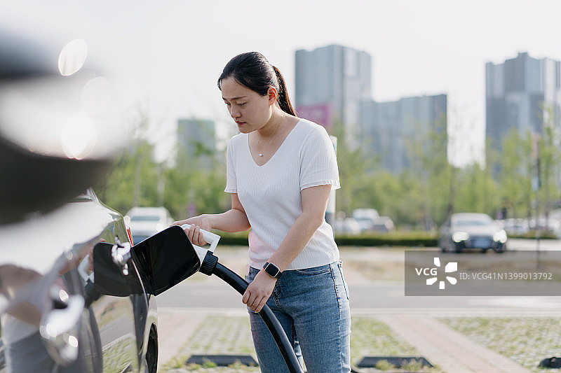 亚洲女人在购物中心停车场为电动汽车充电图片素材