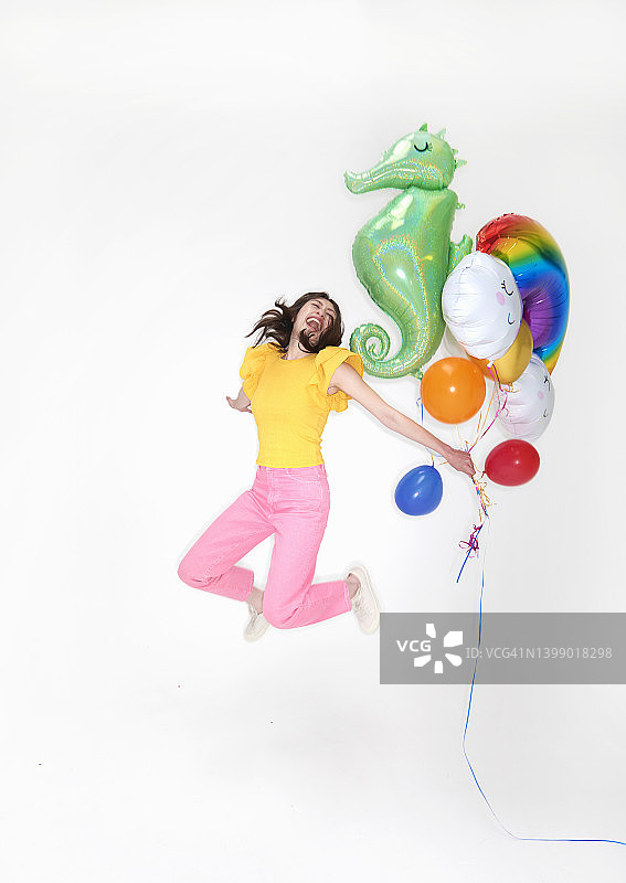年轻女人拿着气球跳跃图片素材