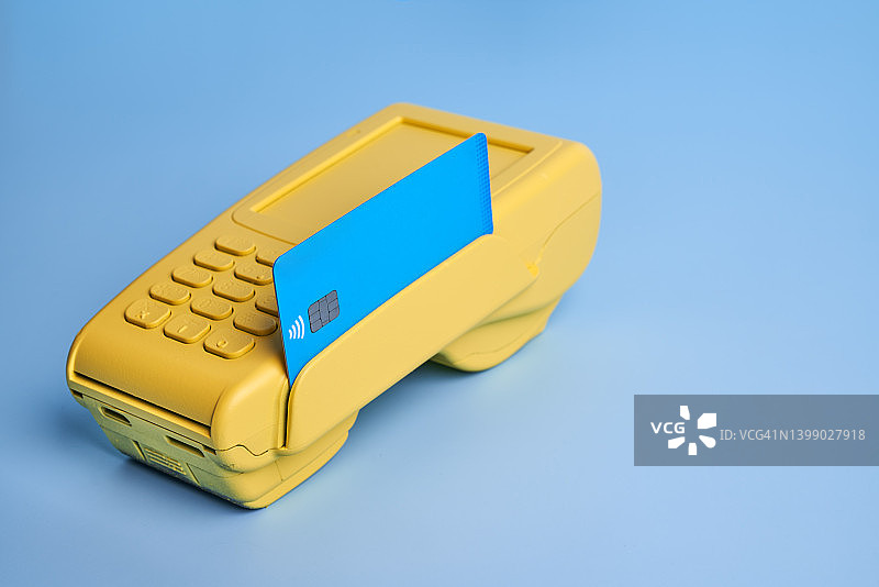 蓝色背景上的黄色信用卡POS机终端图片素材