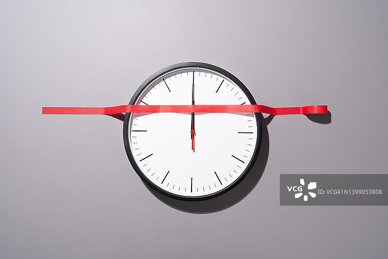 红色胶带粘在时钟指针上，停止时间概念图片素材