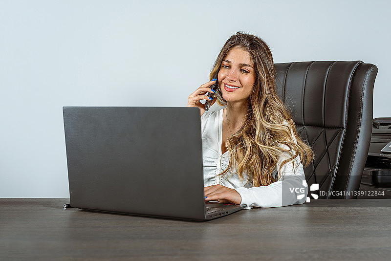 在办公室里微笑打电话的美丽女人图片素材